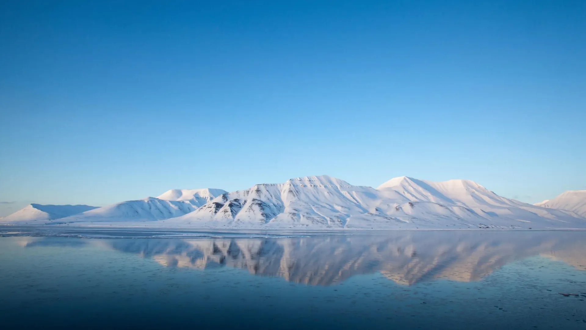 Svalbard mountains above the blue ocean.